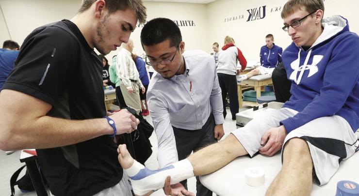 athletic training faculty work with students in a lab setting